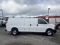 A white 2022 GMC Savana van parked with a sliding side door and multiple windows on the side