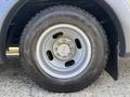A close-up view of a gray wheel featuring a Goodyear Wrangler tire and a steel rim with five lug nuts visible