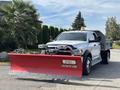 A 2013 RAM 5500 truck with a red Western snow plow attached to the front and a gray dump bed in the back