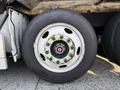 A close-up of a wheel from a 2011 Autocar Xpeditor showing a white rim with green accents and a circular hub with multiple bolts and a central red cap