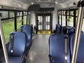 Interior view of a 2021 Ford Transit-350 with blue seats and a foldable wheelchair ramp at the rear
