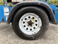 The image shows a close-up of a tire mounted on a blue Genie TZ-34/20 aerial lift with visible wear on the tread and a white rim with multiple bolt holes