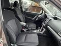 Interior of a 2016 Subaru Forester featuring two front seats with black fabric upholstery and a center console with gear shift and touchscreen display