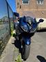 A 2016 Yamaha FJR1300AE motorcycle with a sleek blue design features a large windshield and dual front headlights positioned prominently