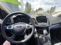 Interior view of a 2015 Ford Escape showing the steering wheel dashboard and center console with controls and displays