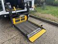 A 2021 Ford Transit-350 with a deployed wheelchair lift featuring yellow handles and a metal grate surface