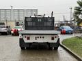 A 2019 Freightliner M2 truck with a flatbed and a mesh cargo area is parked with its back facing the viewer showing dual exhaust pipes on each side