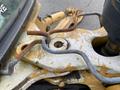A close-up view of a 2012 John Deere 310SJ construction machine showing a worn metal surface with rusted and bent metal components