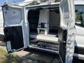 A 2019 Ford Transit 350 with open side and rear doors revealing a spacious interior designed for utility and organization