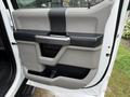 Door panel of a 2020 Ford F-550 featuring a gray and black color scheme with a handle and storage compartment