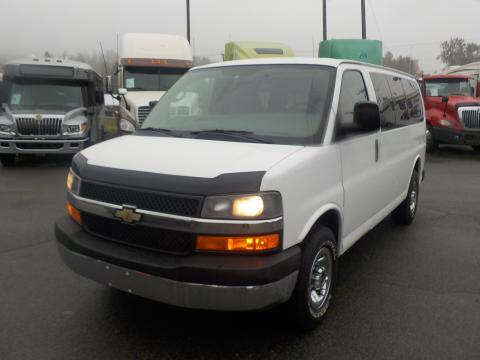 A 2011 Chevrolet Express van in white with a black front grille and headlights parked in a lot
