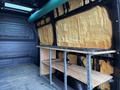 A 2022 Mercedes-Benz Sprinter van interior showing insulation on the walls and a wooden shelving unit against the side