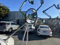 A 2006 Freightliner M2 106 truck's side mirror reflecting a view of parked vehicles and equipment in a work yard