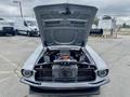 A 1968 Ford Mustang two door convertible with the hood raised revealing a detailed engine compartment