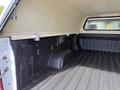 An empty truck bed of a 2019 Chevrolet Silverado 1500 with a bed liner and a cover compartment on the side