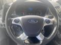 Steering wheel of a 2017 Ford Transit with a prominent Ford logo and controls for audio and cruise settings