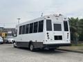 A white 2020 Chevrolet Express shuttle bus with large windows and a wheelchair access door on the rear side
