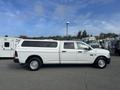A white 2012 RAM 2500 pickup truck with a camper shell on the bed facing to the left