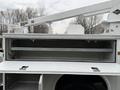 A 2001 Ford F-350 truck with an open utility bed displaying a storage compartment and a metal rail inside