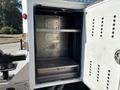 An open storage compartment of a 2011 Ford F-550 with metal shelves and a black interior