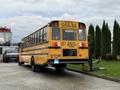 A yellow 2014 Freightliner B2 school bus with large windows and a stop sign extended from the side