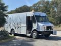 A 2008 Workhorse W62 delivery truck with a silver metallic exterior and multiple compartments on the sides parked on a roadside