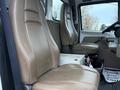 Interior of a 2004 Sterling LT9500 featuring two beige leather seats with armrests and a central storage compartment between them