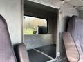 Interior view of a 2013 International Durastar 4300 showing the driver's compartment and an opening leading to the cargo area with two seats visible