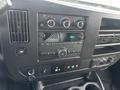 The dashboard of a 2022 GMC Savana featuring climate controls audio system and a digital display for the time