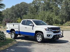 A 2017 Chevrolet Colorado with a white body and blue accents featuring a utility bed and a winch attached to the front