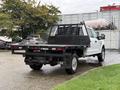 A white 2019 Ford F-350 SD pickup truck with a flatbed and black tool rack at the rear is parked with its back facing the viewer