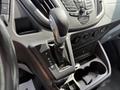 The gear shift of a 2016 Ford Transit showing the gear positions P R N D M with a leather cover and a silver knob