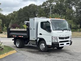 A 2015 Mitsubishi Fuso FE160 truck with a dump bed and a silver cargo box on the rear parked on a paved surface