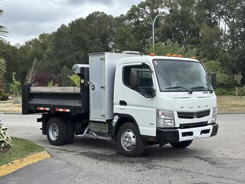 A 2015 Mitsubishi Fuso FE160 truck with a dump bed and a silver cargo box on the rear parked on a paved surface