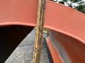 A close-up of a measuring tape placed against an orange surface of a 2012 International 7400 truck