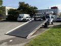 A 2022 Ford F600 tow truck with a flatbed ramp lowered ready for loading vehicles