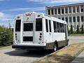 A 2020 Chevrolet Express bus with a white body and black accents parked with large windows and a wheelchair access feature on the rear