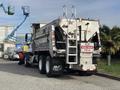 A 2013 Freightliner 114SD dump truck with a silver body, dual rear axles, and a large cargo bed featuring safety signs and a ladder on the side