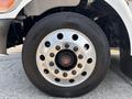 Close-up of a silver wheel rim with a black tire featuring a prominent wheel hub and multiple lug nuts, mounted on a 2020 Peterbilt 330 truck