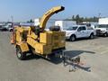 A 2010 Vermeer Corporation BC1200XL wood chipper in yellow with a large chute and attached trailer hitch