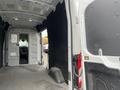 Interior view of a 2023 Ford Transit showing the cargo area and driver's cabin with a focus on the spacious, unfinished loading space