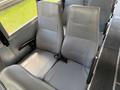 Two gray bus seats with vertical ribbed design and seat belts visible in the foreground
