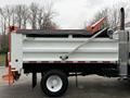 A 2012 International 7400 dump truck with an open tailgate and a raised rear compartment for unloading materials