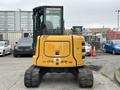 A 2017 John Deere 50G excavator with a yellow and black exterior positioned with its rear facing the viewer showcasing its tracks and cabin