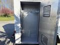 An empty metal storage compartment with an open door featuring hooks and vent grilles inside the 2012 Ford Econoline E-450