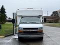 A white 2015 Chevrolet Express with an extended roof is facing forward with its driver's side door open