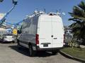 A 2023 Mercedes-Benz Sprinter 2500 van in white with roof racks and a rear view focusing on its sleek design and spacious cargo area