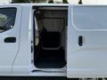 A 2021 Nissan NV200 van with an open side door revealing the cargo area that has a dark floor and no visible items inside