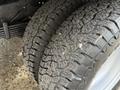 Close-up of two worn tires with deep tread patterns mounted on wheels of a 2015 GMC Savana