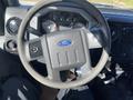 A close-up of the steering wheel of a 2016 Ford F-250 SD featuring the Ford logo and various control knobs and gauges